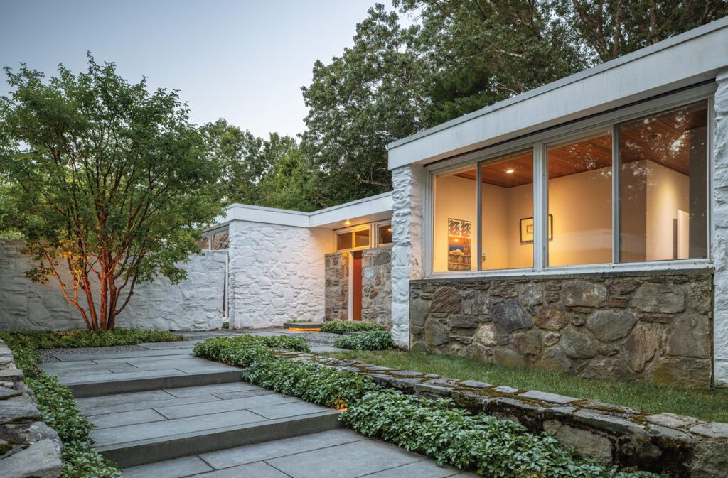 Modern courtyard entrance with stone walls, bluestone steps, and layered greenery.