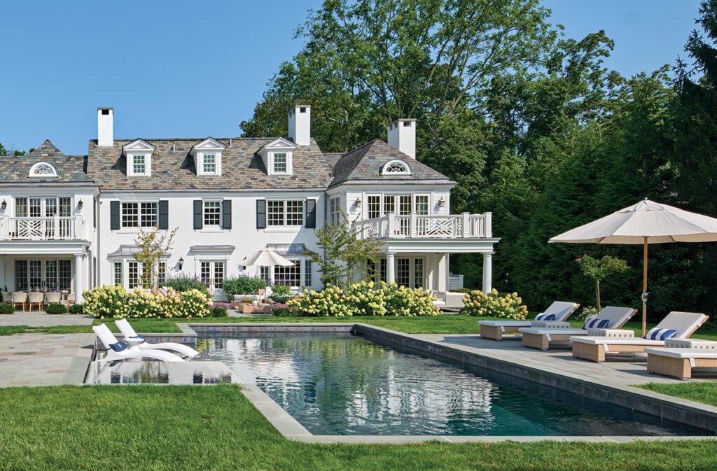 Rear view of renovated Greenwich Colonial with pool, terraces, and landscaped backyard.