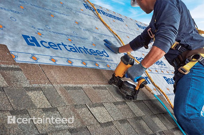 Roofing contractor securing CertainTeed roofing underlayment before installing asphalt shingles.